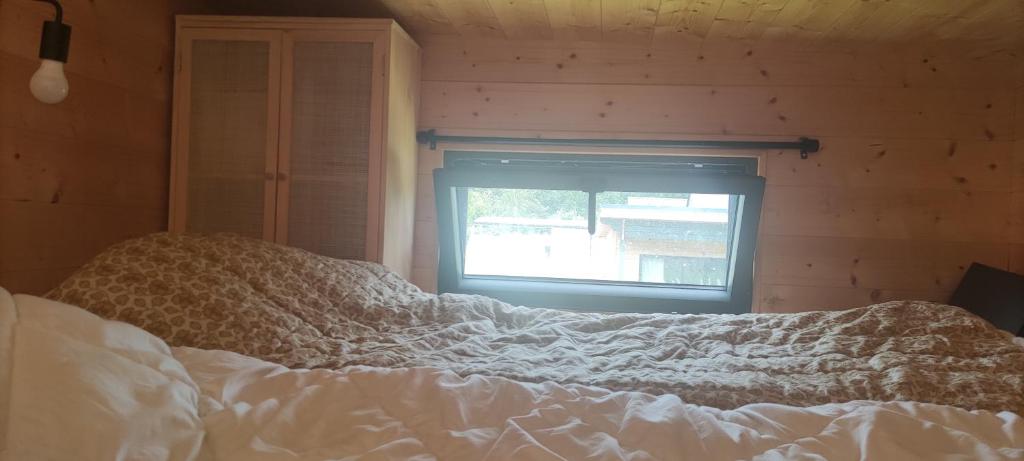 un lit dans une chambre avec une fenêtre dans l'établissement Tiny house bucolique, à Saint-Brieuc-de-Mauron