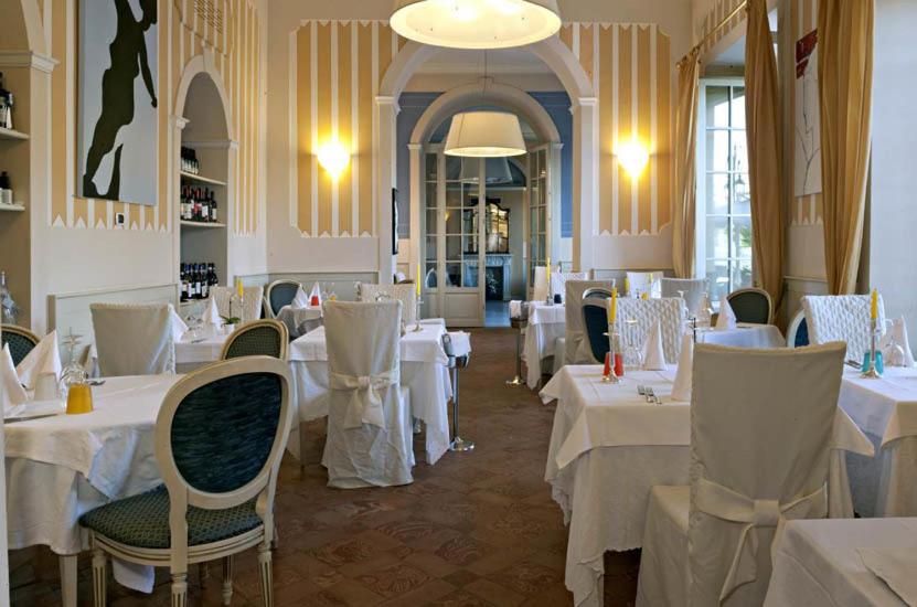 une salle à manger avec des tables et des chaises avec des nappes blanches dans l'établissement Hotel Cannobio, à Cannobio