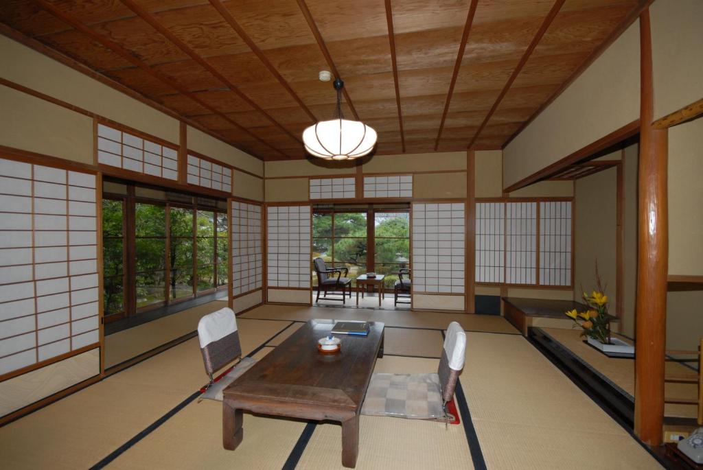un salon avec une table, des chaises et des fenêtres dans l'établissement Sansuien, à Yamaguchi