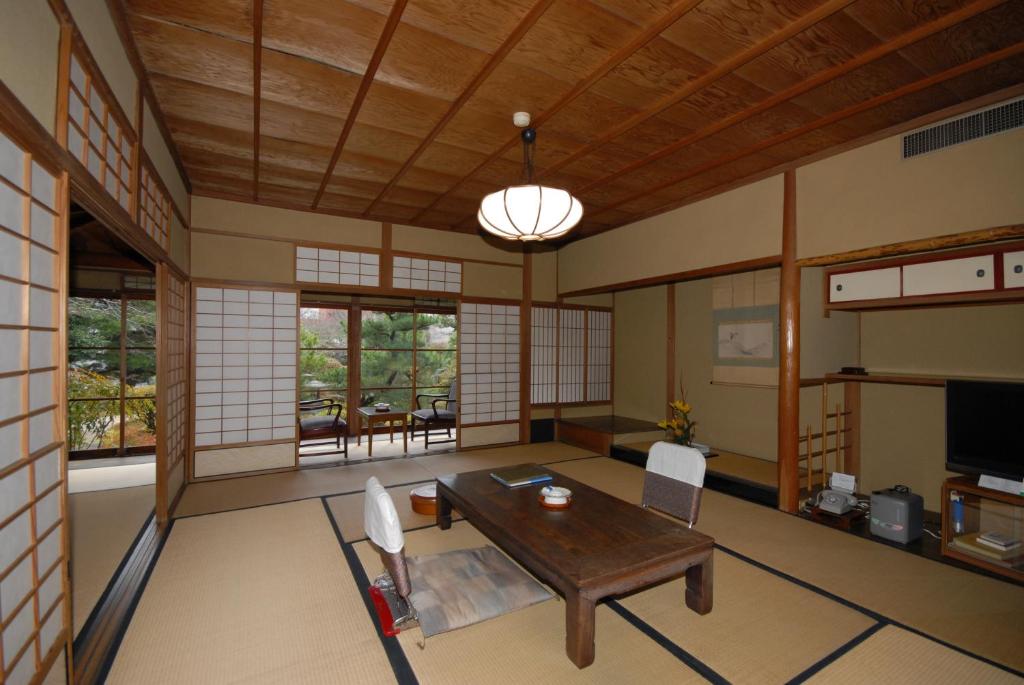 un salon avec une table et des chaises en bois dans l'établissement Sansuien, à Yamaguchi