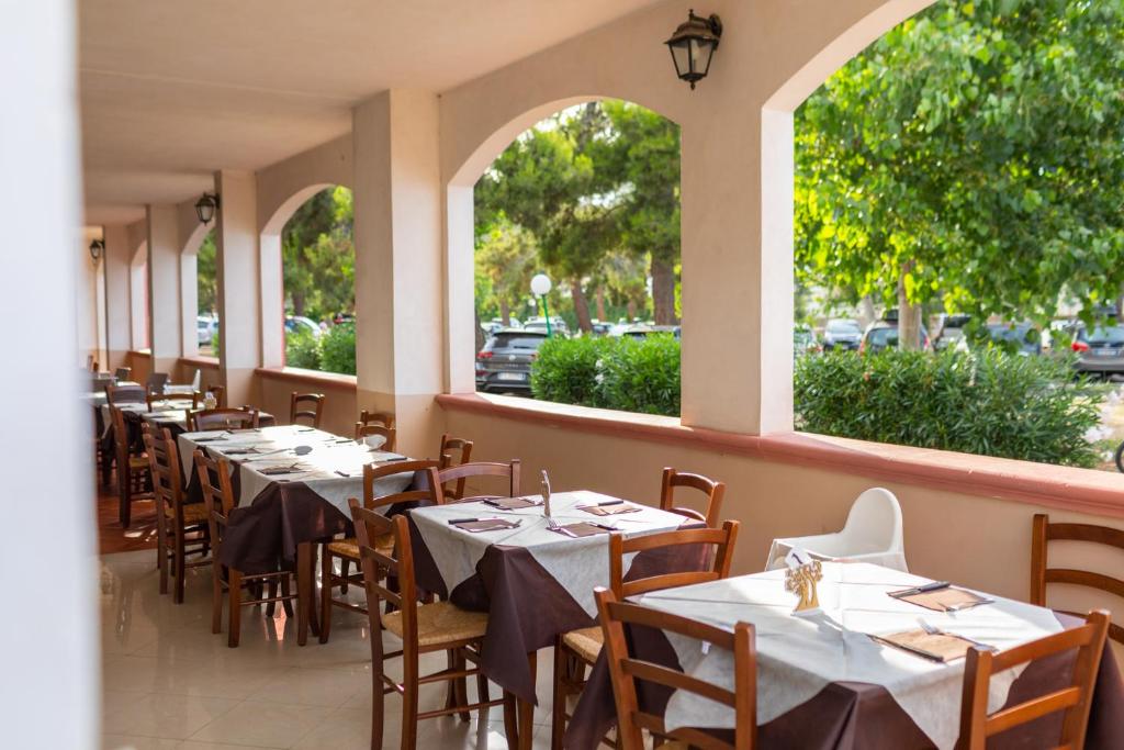 une rangée de tables dans un restaurant avec fenêtres dans l'établissement Village La Canzone del Mare, à Vieste