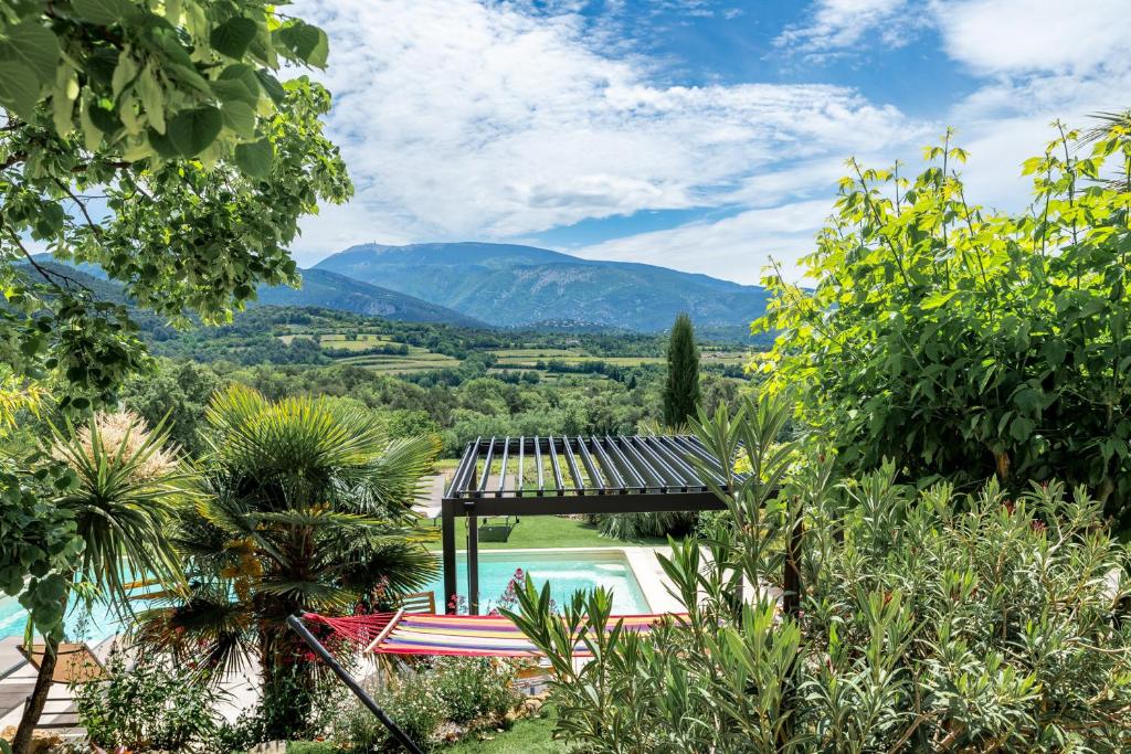 un jardin avec une piscine et des montagnes en arrière-plan dans l'établissement Gite Les Aiguillans, à Mérindol-les-Oliviers