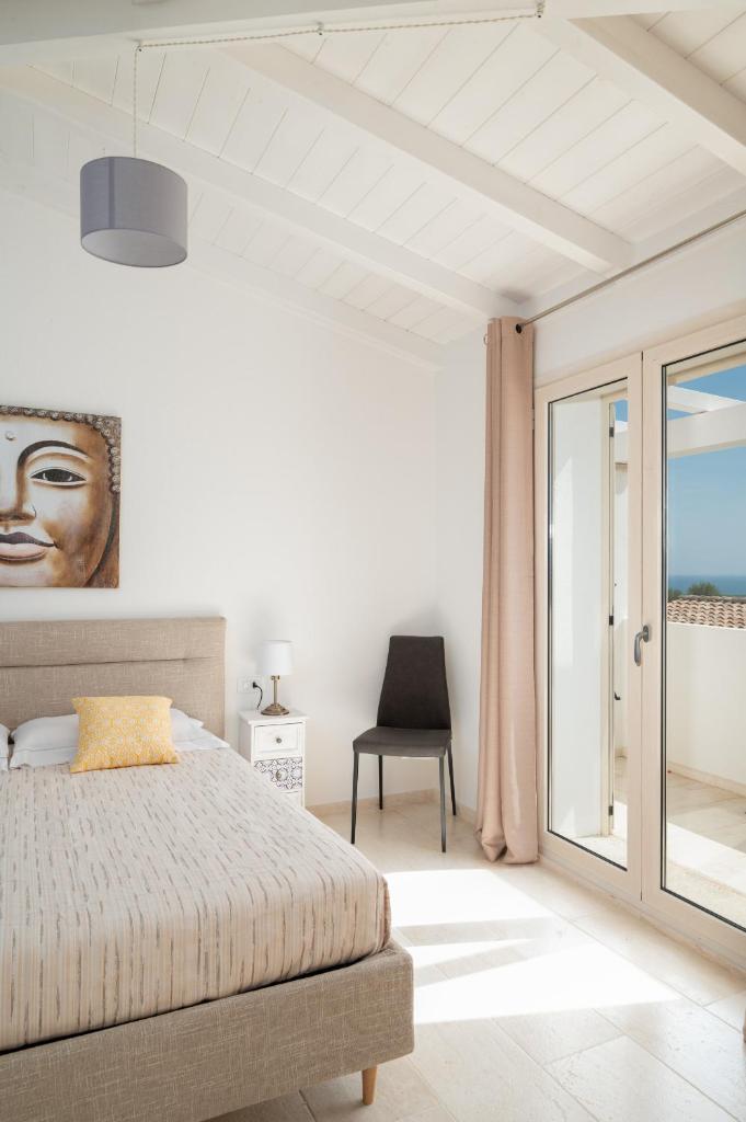 une chambre avec un lit, une fenêtre et une chaise dans l'établissement Bellevue by Klodge, à Budoni