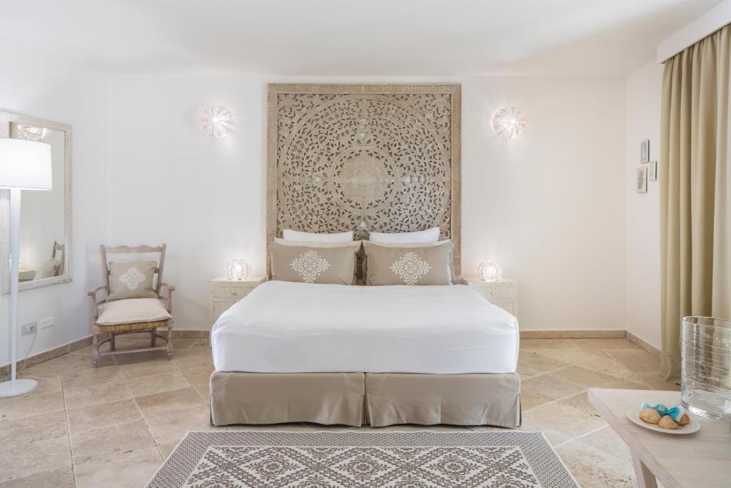 une chambre blanche avec un lit et une chaise dans l'établissement Falkensteiner Resort Capo Boi, à Villasimius