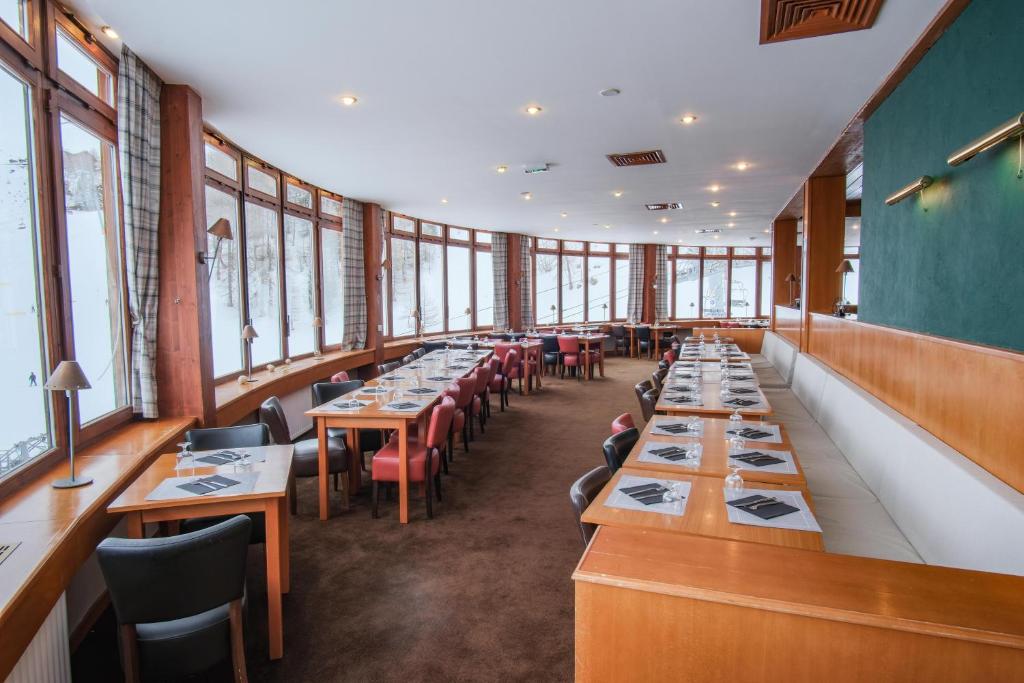 une rangée de tables dans un restaurant avec fenêtres dans l'établissement Hôtel La Plagne Le Terra Nova, à La Plagne