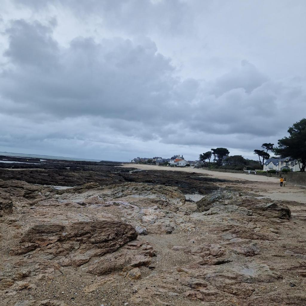 une plage avec des rochers et l'océan par temps nuageux dans l'établissement Camping de Bayadene, à Piriac-sur-Mer