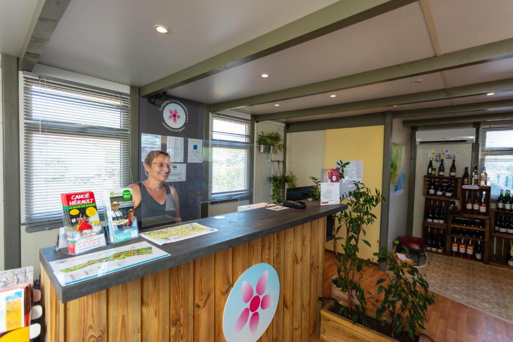une femme debout à un comptoir dans un magasin dans l'établissement Camping Les Amandiers, à Castelnau-de-Guers