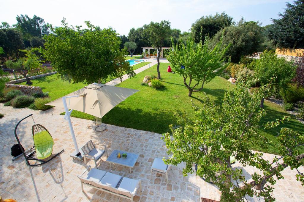 une vue aérienne d'un jardin avec un parasol et des chaises dans l'établissement Trullo Divina (service fee waived), à Selva di Fasano