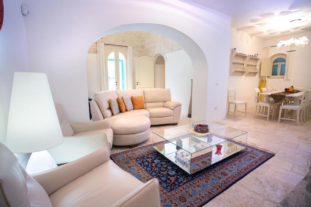 Elle comprend un salon doté d'un mobilier blanc et d'une table basse en verre. dans l'établissement Trullo Divina (service fee waived), à Selva di Fasano