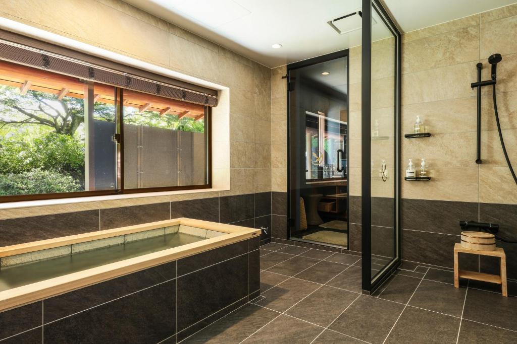 une salle de bain avec baignoire et douche en verre dans l'établissement Beautiful Japanese Garden Kagetsu, à Fuefuki