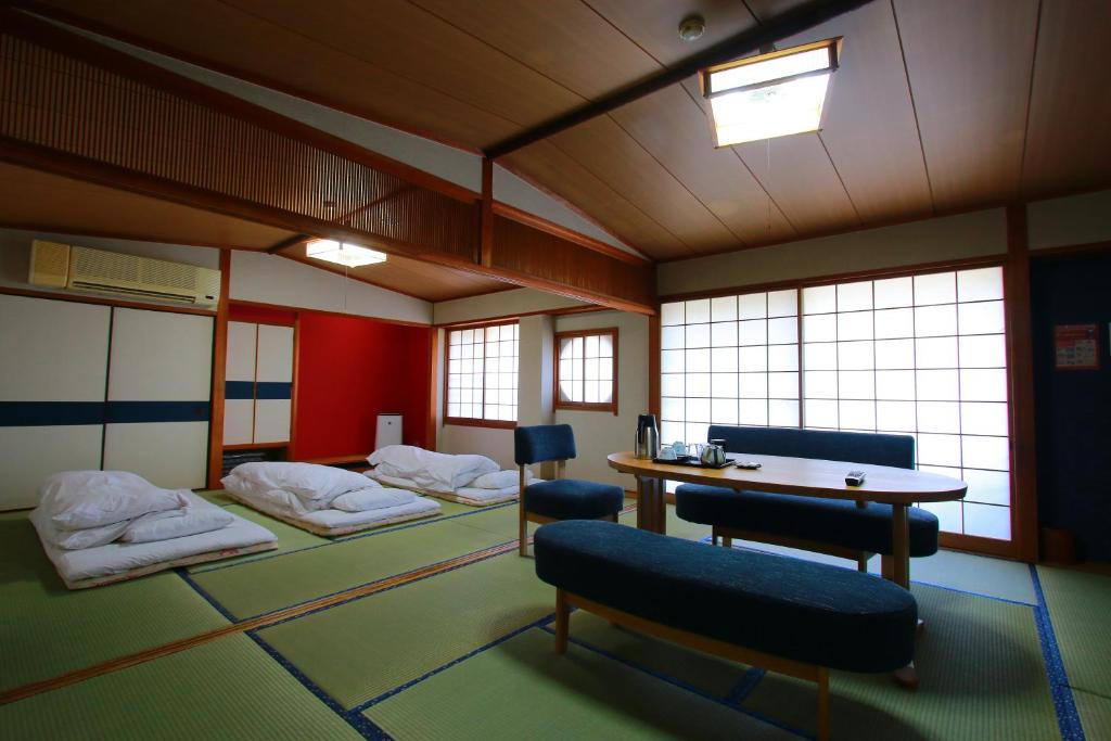 Cette chambre comprend 3 lits, une table et des chaises. dans l'établissement 旅館　松乃湯, à Kutami