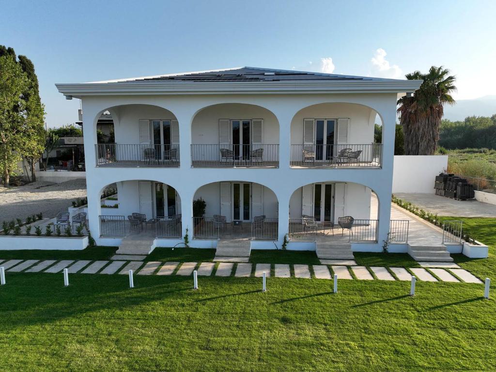 une grande maison blanche avec une pelouse dans l'établissement Villa Achiropita, à Rossano