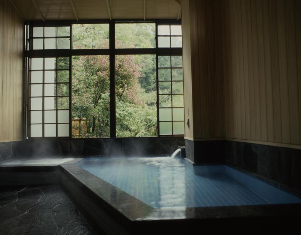 d'une salle de bains avec une piscine d'eau et des fenêtres. dans l'établissement Sansuien, à Yamaguchi 37 autres photos