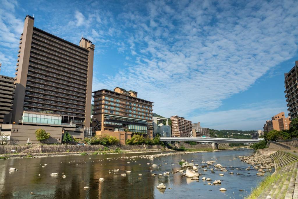 une rivière avec des cygnes dans une ville avec des bâtiments dans l'établissement Hotel Wakamizu, à Takarazuka