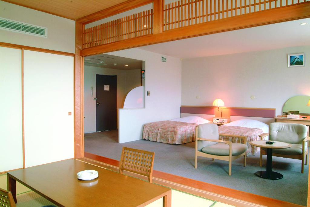 une chambre avec deux lits et une table et des chaises dans l'établissement Horoshin Onsen Hotarukan, à Numata