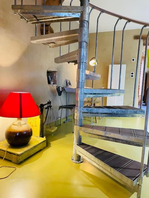 un escalier en colimaçon dans une chambre avec une lampe rouge dans l'établissement Gîte Les Grangettes*Piscine*Cadre bucolique, à Campagnac-lès-Quercy 7 autres photos