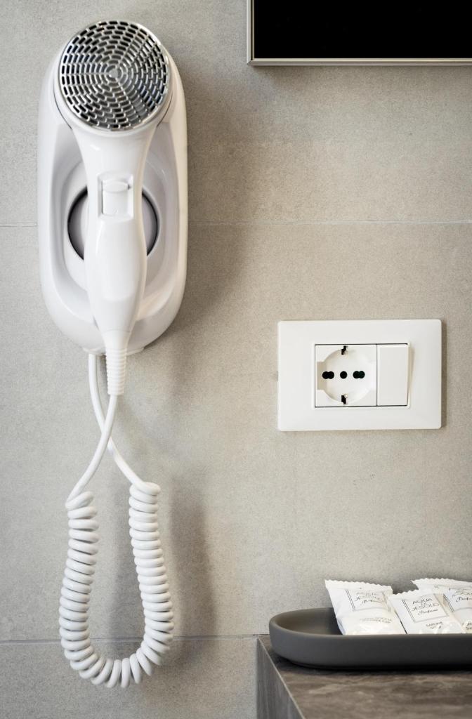 un sèche-cheveux blanc accroché au mur dans l'établissement Hotel Laurin, à Lido di Jesolo