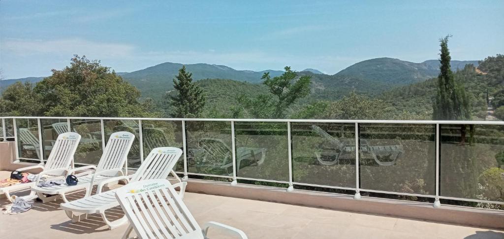 d'un balcon avec des chaises blanches et une vue sur les montagnes. dans l'établissement Le Bungalow Bleu Domaine des Canebieres Golfe de St Tropez, au Muy 7 autres photos