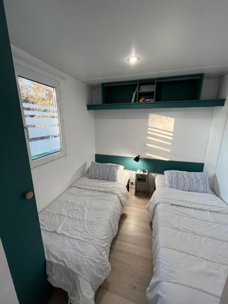 une chambre avec deux lits et une fenêtre dans l'établissement Mobil-home Camping Oasis, à Roquebrune-sur Argens