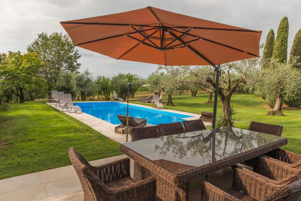 - une table avec un parasol à côté de la piscine dans l'établissement Villa Minerva, à Lazise