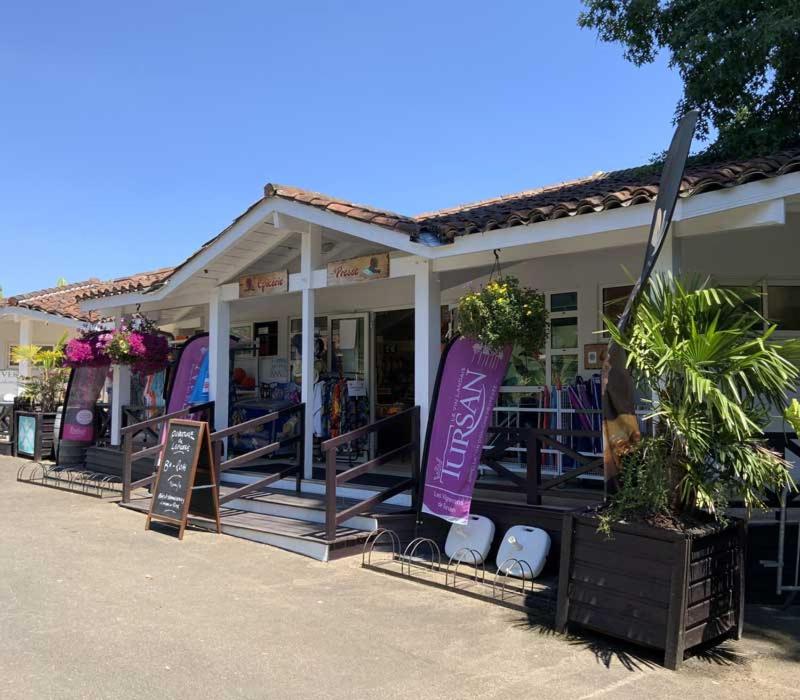 un magasin avec des panneaux devant un bâtiment dans l'établissement Camping le Sen Yan, à Mézos