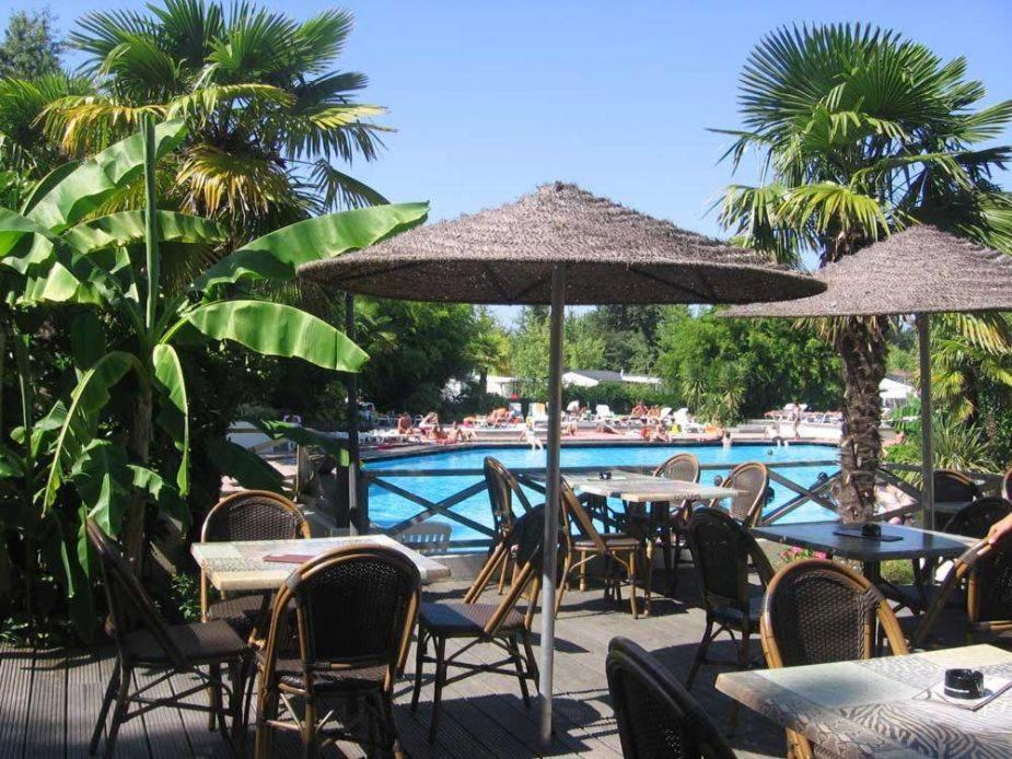 un groupe de tables et de parasols à côté d'une piscine dans l'établissement Camping le Sen Yan, à Mézos