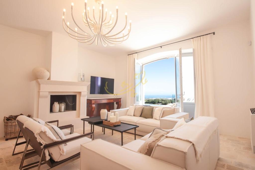Elle comprend un salon doté d'un mobilier blanc et d'un lustre. dans l'établissement TD Tenuta Donna Madia Sea View Pool Over Vineyard, à Monopoli