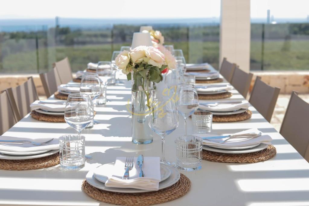 une grande table avec des assiettes, des verres et des fleurs dans l'établissement TD Tenuta Donna Madia Sea View Pool Over Vineyard, à Monopoli
