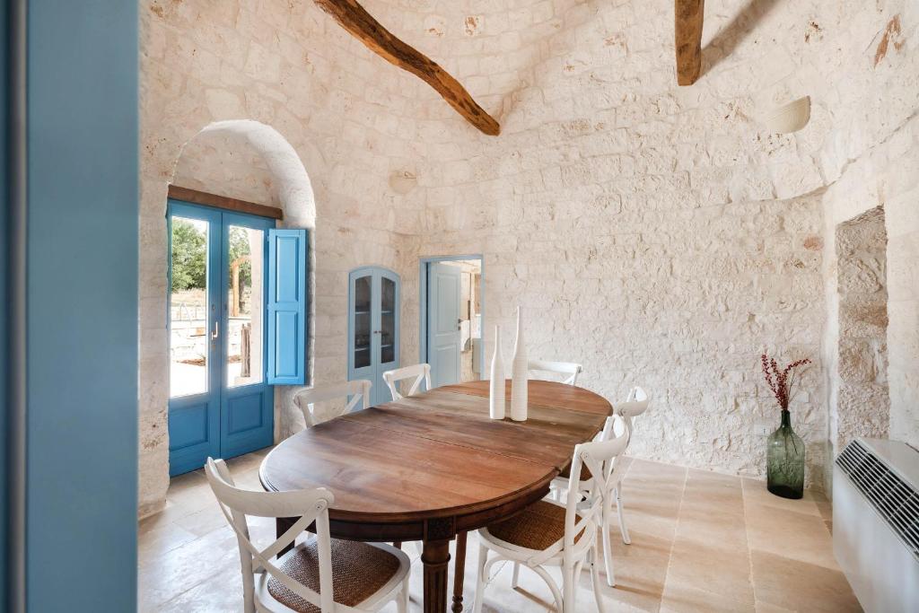 une salle à manger avec une table en bois et des chaises blanches dans l'établissement Trullo Pia, à Monopoli