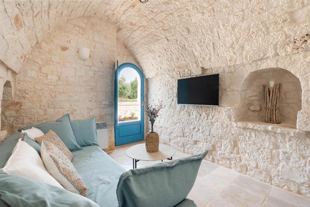 - un salon avec un canapé bleu et un mur en pierre dans l'établissement Trullo Pia, à Monopoli