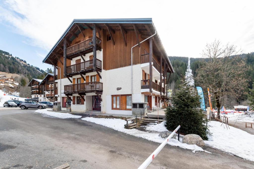 un grand bâtiment dans la neige à côté d'un parking dans l'établissement Le Marmotton, à La Giettaz