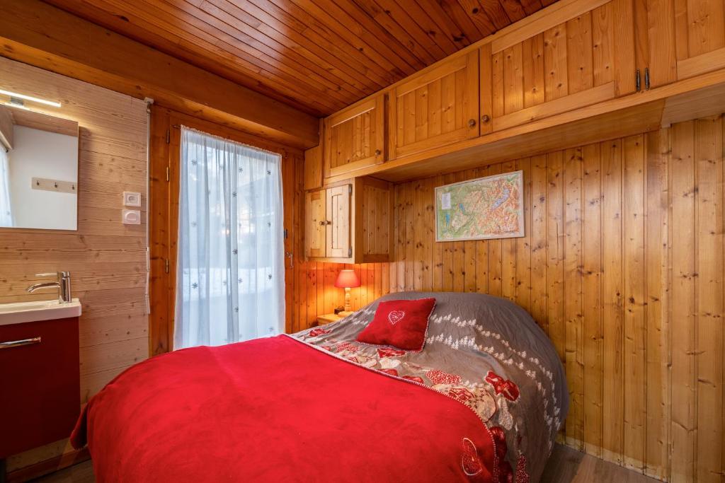 Cette chambre en bois comprend un lit rouge. dans l'établissement Le Marmotton, à La Giettaz