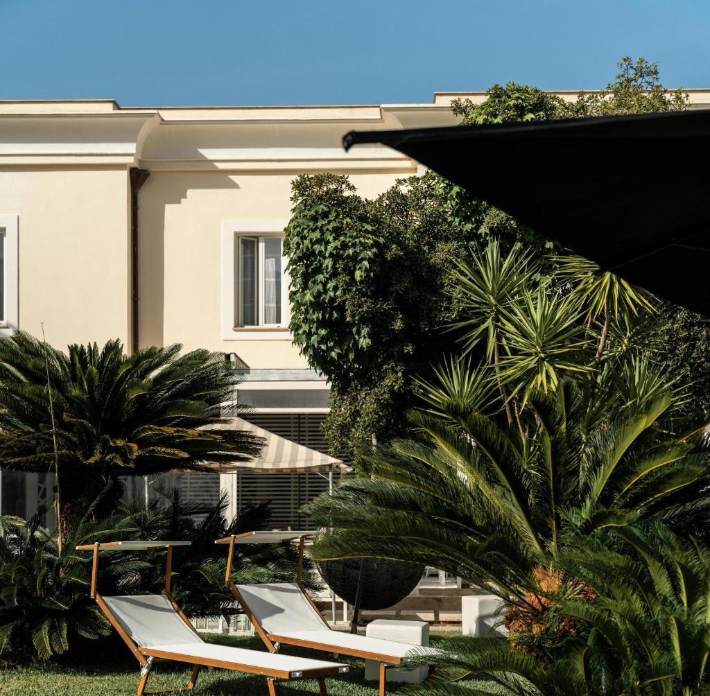 un groupe de chaises et de parasols devant un bâtiment dans l'établissement Relais Corte Degli Aragonesi, à Ischia