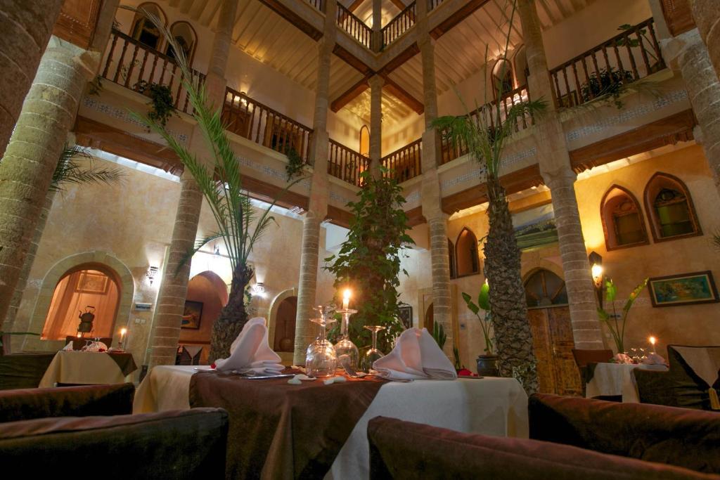un restaurant avec des tables et des chaises dans un bâtiment dans l'établissement Palais Des Remparts, à Essaouira