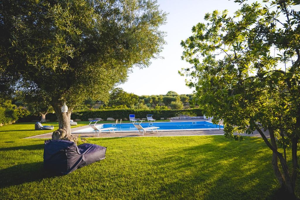 une personne posant sur l'herbe sous un arbre près d'une piscine dans l'établissement Villa Elenik - Puglia Mia Apartments, à Triggianello