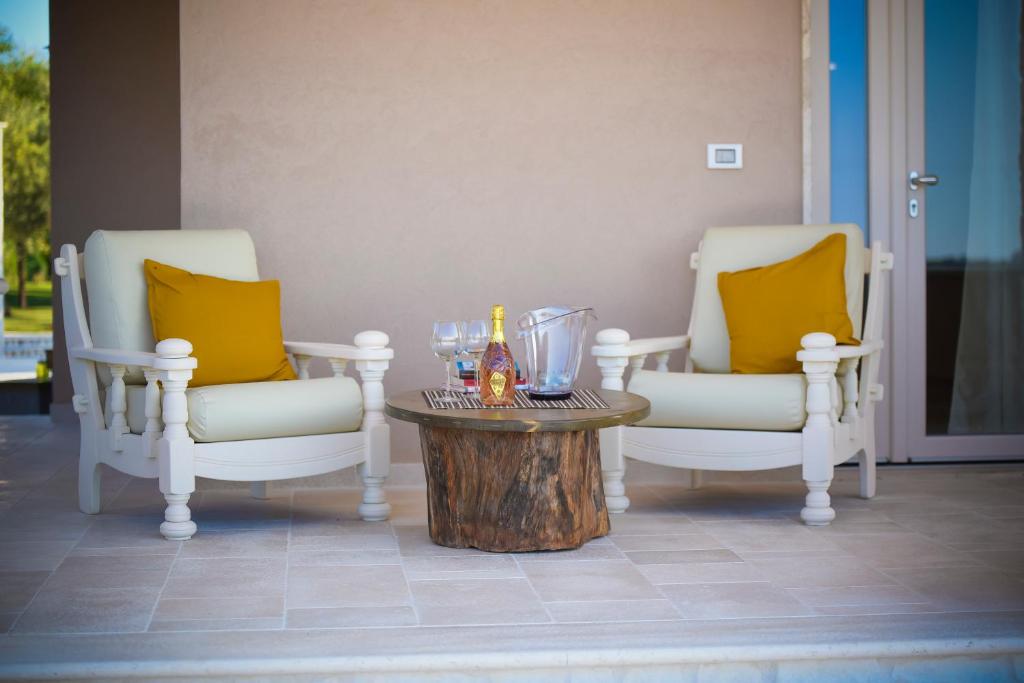 2 chaises et une table avec des bouteilles et des verres dans l'établissement Villa Elenik - Puglia Mia Apartments, à Triggianello