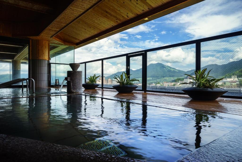 une piscine avec des plantes dans un bâtiment avec vue dans l'établissement Aburaya Tousen, à Yamanouchi