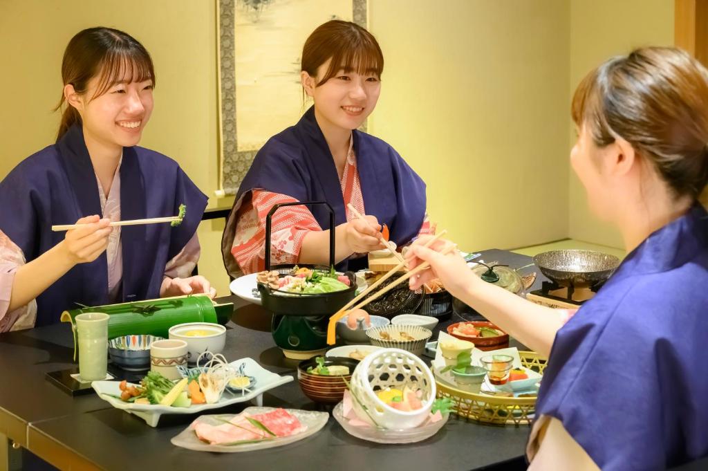 Un groupe de trois femmes assises autour d'une table et mangeant de la nourriture dans l'établissement Fukuichi, à Shibukawa