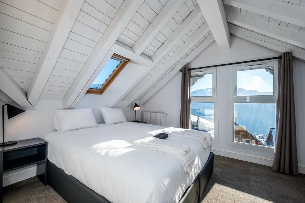 une chambre avec un grand lit blanc et une fenêtre dans l'établissement PopAlp, à L'Alpe-d'Huez