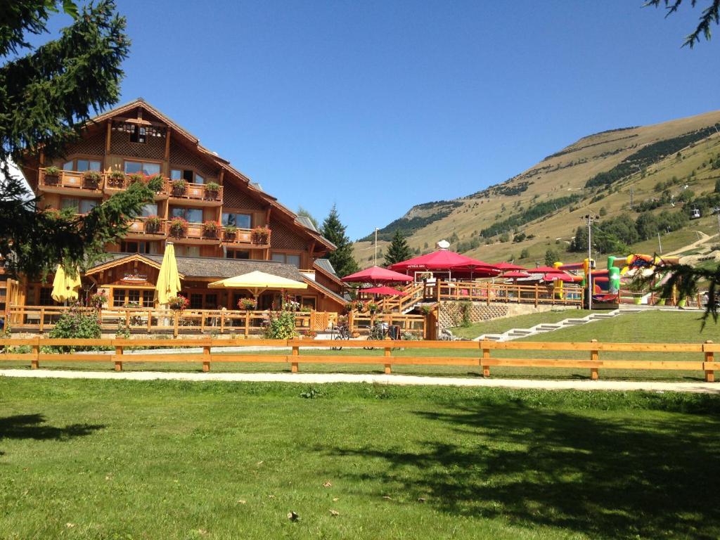 un grand bâtiment avec une clôture devant lui dans l'établissement Hotel Cote Brune, à Les Deux Alpes