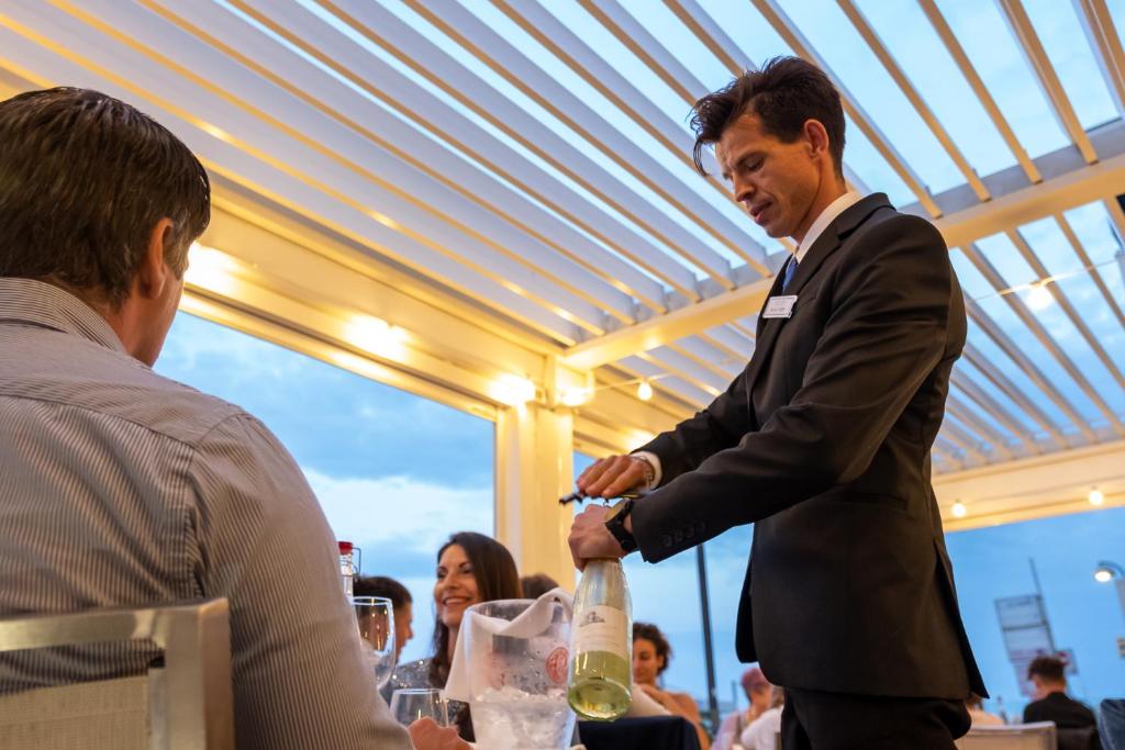 un homme en costume tenant une bouteille de vin dans l'établissement Hotel Agostini, à Bellaria-Igea Marina 33 autres photos