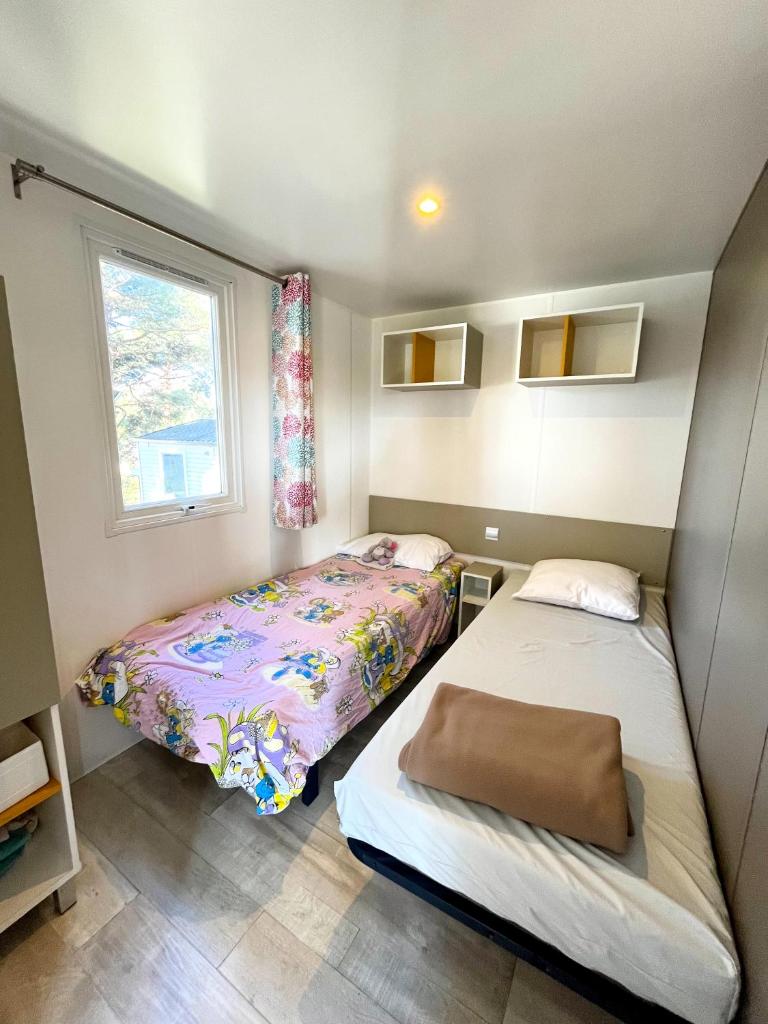 une petite chambre avec deux lits et une fenêtre dans l'établissement Mobil-home dans camping 4*, à Saint-Laurent-du-Verdon