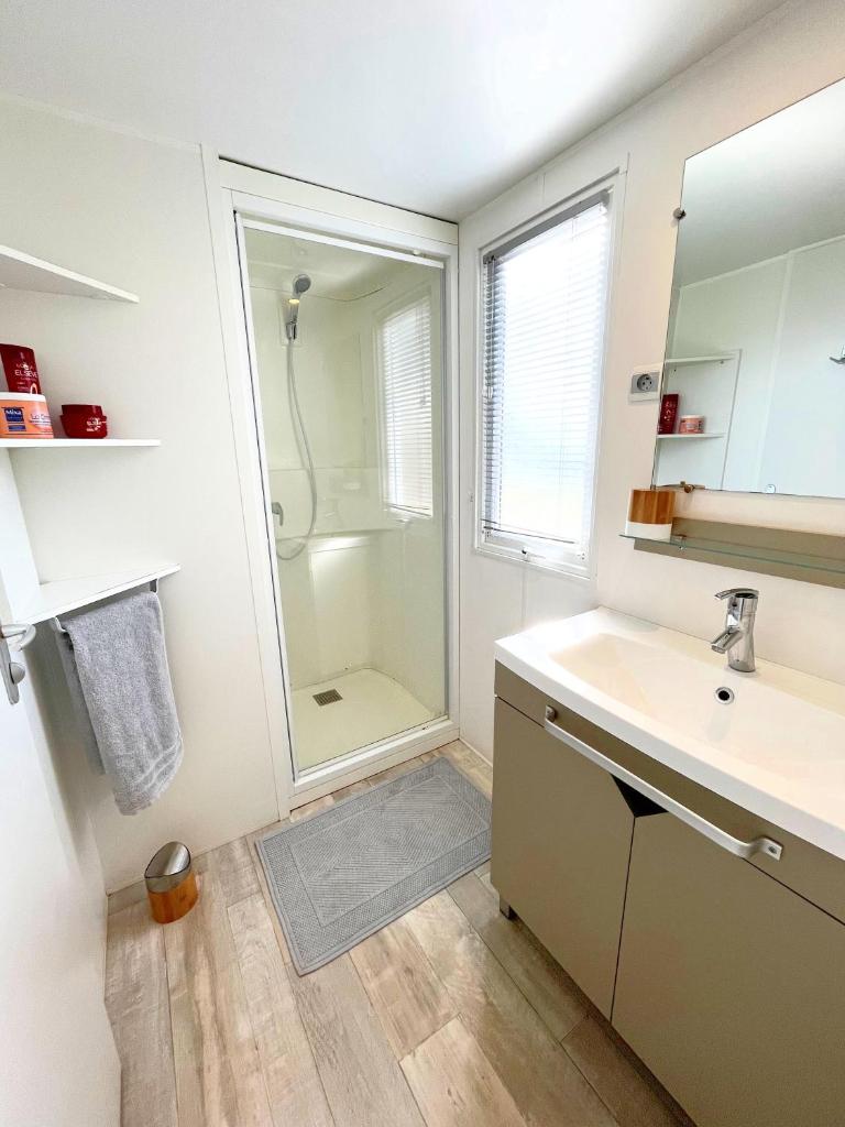 une salle de bain blanche avec une douche et un lavabo dans l'établissement Mobil-home dans camping 4*, à Saint-Laurent-du-Verdon