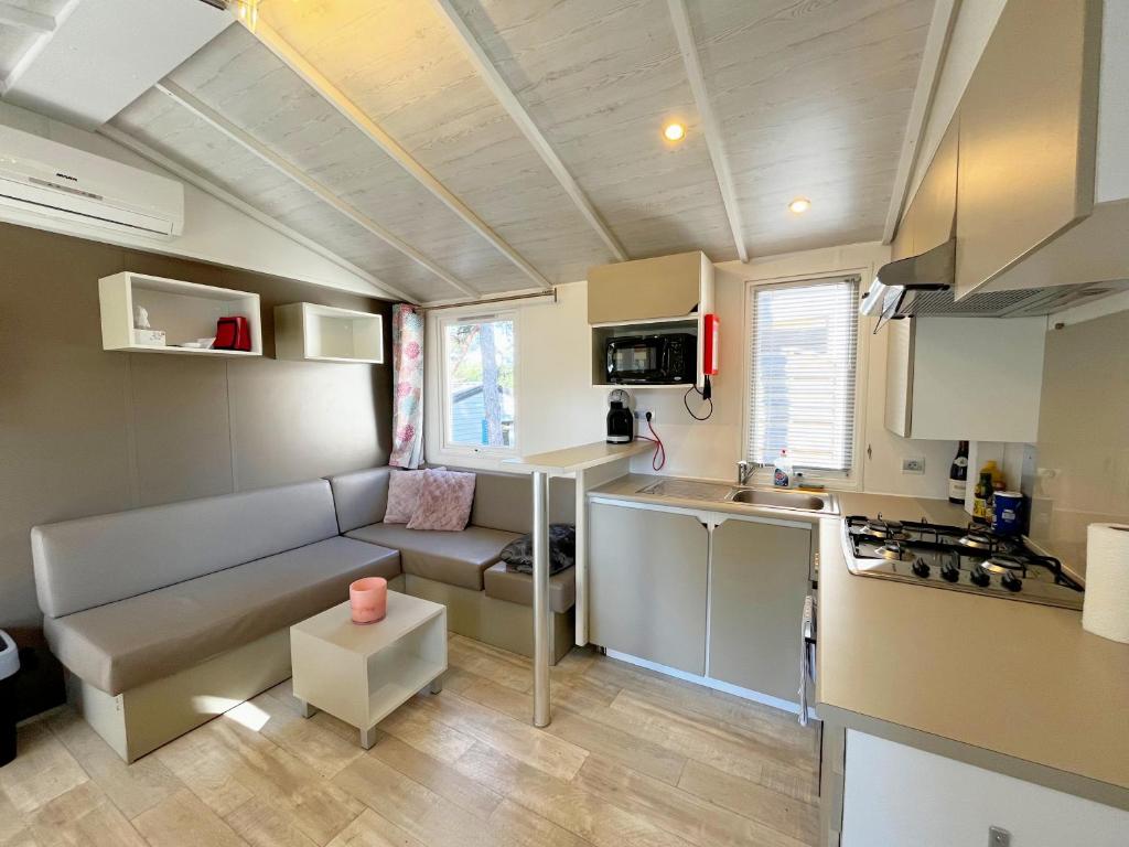 un petit salon avec un canapé et une cuisine dans l'établissement Mobil-home dans camping 4*, à Saint-Laurent-du-Verdon