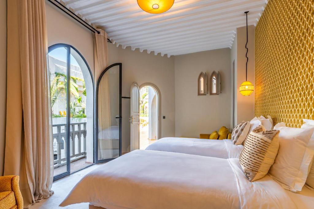 une chambre avec un grand lit blanc et un balcon dans l'établissement Riad XO, à Marrakech