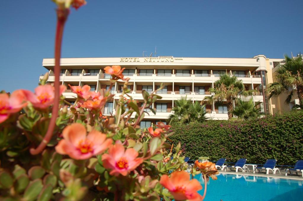 un bâtiment d'hôtel avec des chaises et des fleurs devant lui dans l'établissement Hotel Nettuno, à Catane