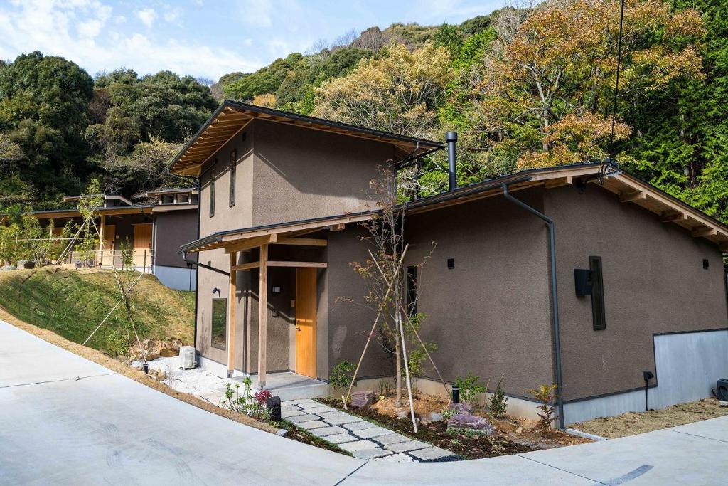 une petite maison avec une colline en arrière-plan dans l'établissement 横川温泉湯殿ととのゆ, à Shimoda