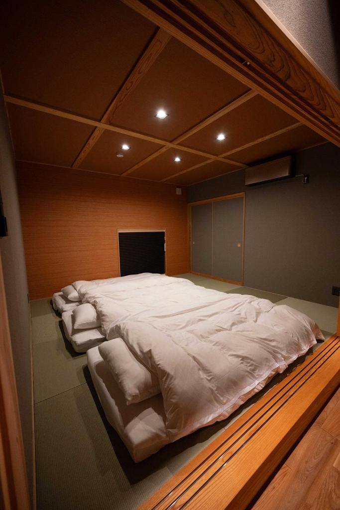 Cette chambre comprend un grand lit avec des draps blancs. dans l'établissement 横川温泉湯殿ととのゆ, à Shimoda 130 autres photos