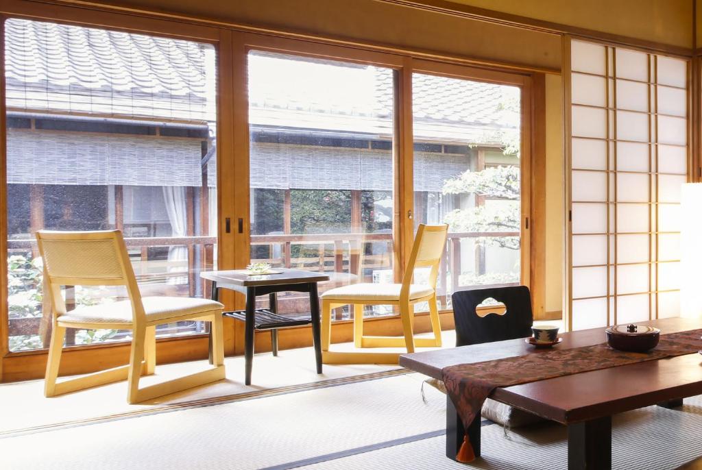 une chambre avec des chaises, une table et des fenêtres dans l'établissement Ryokan Sanga, à Kyoto