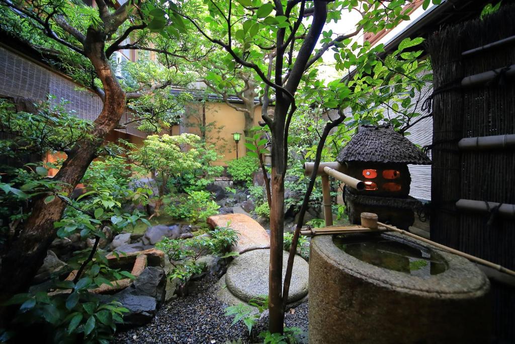 un jardin avec un petit étang et une statue dans l'établissement Ryokan Sanga, à Kyoto
